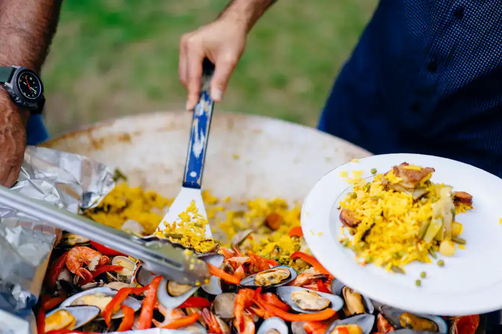 Cocinero preparando paella grande en un evento al aire libre