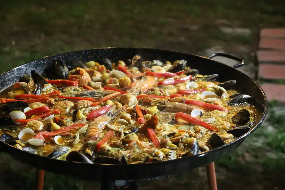 Paella cocinándose en vivo en una gran paellera durante un evento